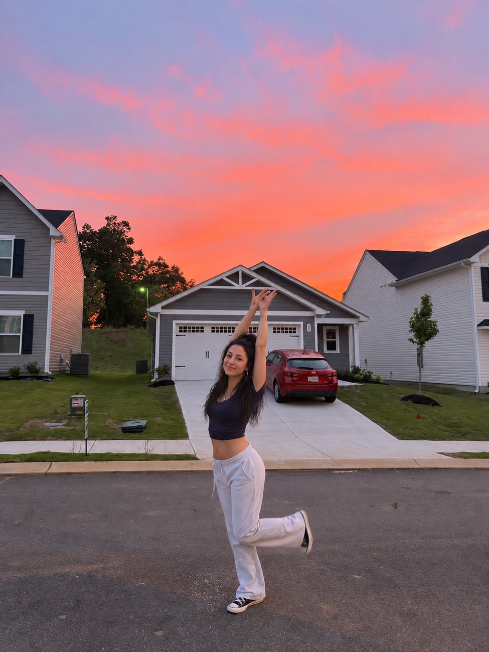 A smiling woman stretching in front of a house at sunset