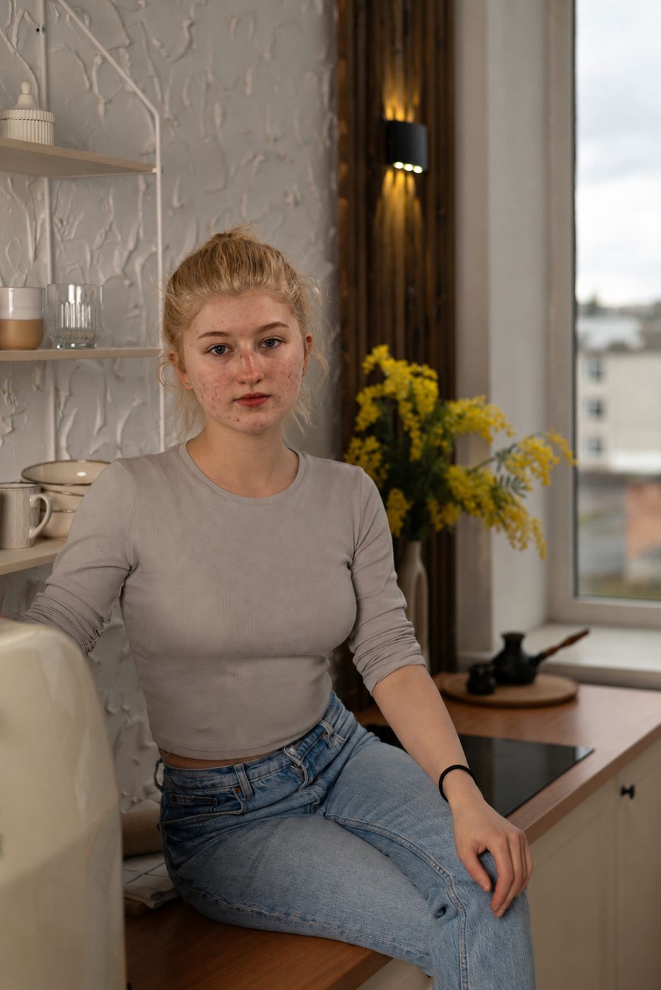 A young woman sitting on her kitchen counter at home