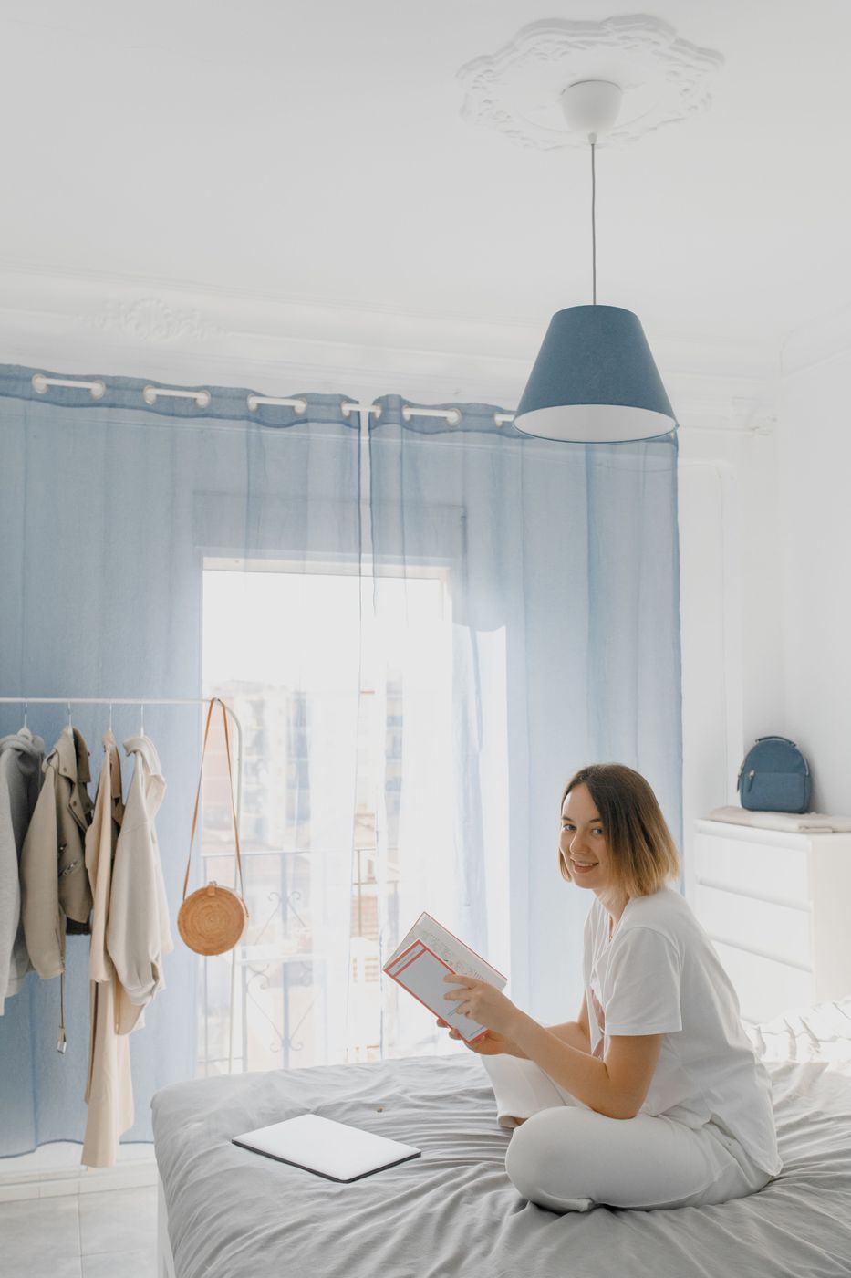 A woman reading on her bed in a bright, airy bedroom